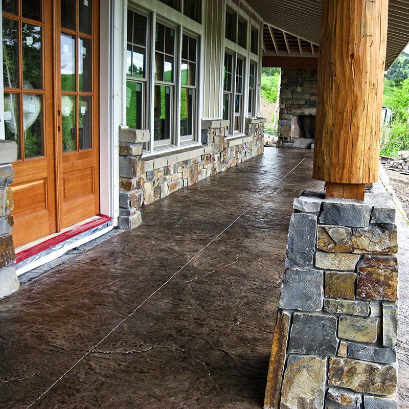 A porch with a stone wall and wooden doors
