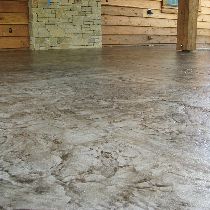A concrete floor with a stone wall in the background