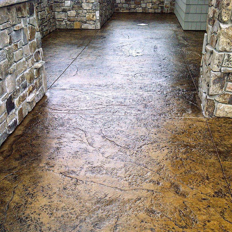 A concrete floor with a stone wall in the background