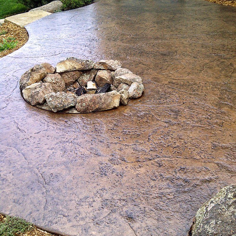 A fire pit is surrounded by rocks on a concrete patio.