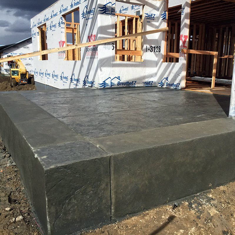 A large concrete block is sitting in front of a house under construction