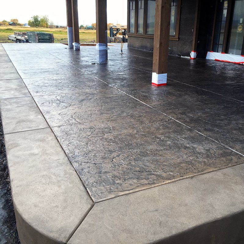 A concrete patio with a wooden structure in the background
