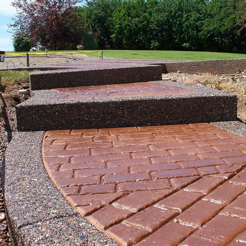A brick walkway leading to a grassy field