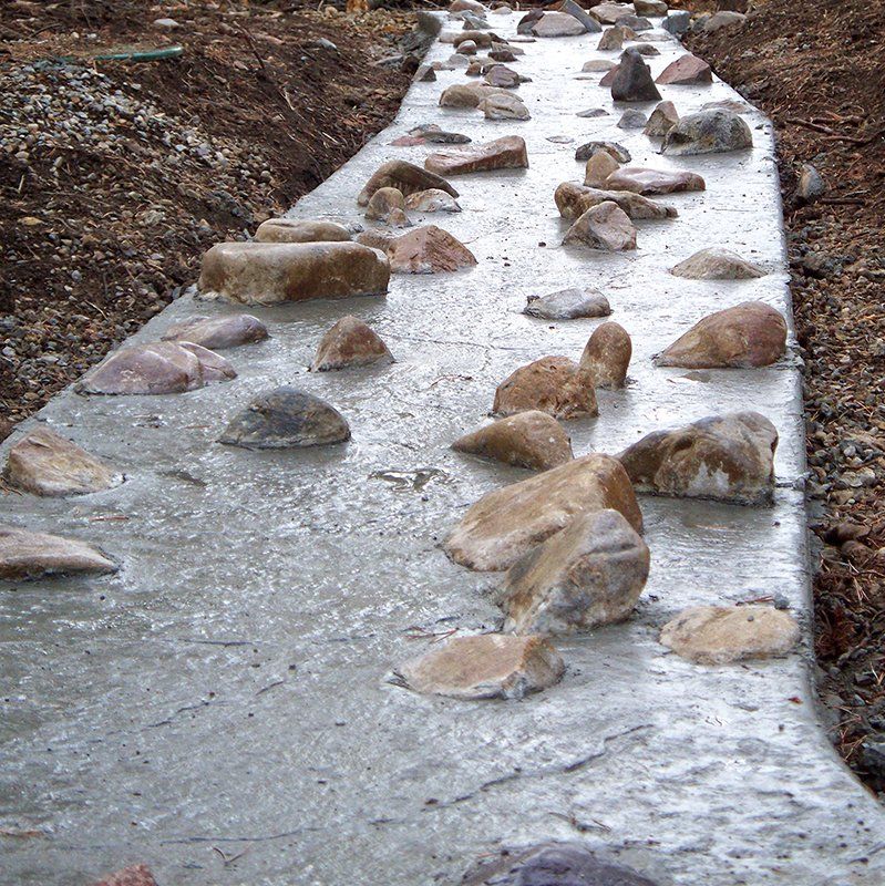 A concrete walkway with rocks on the side of it