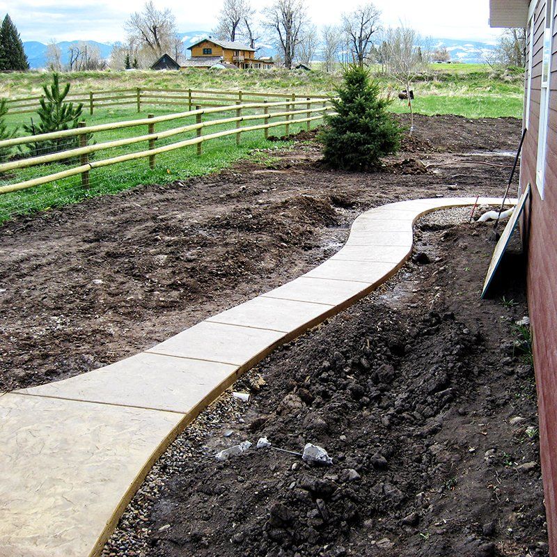 A concrete walkway with a wooden fence in the background