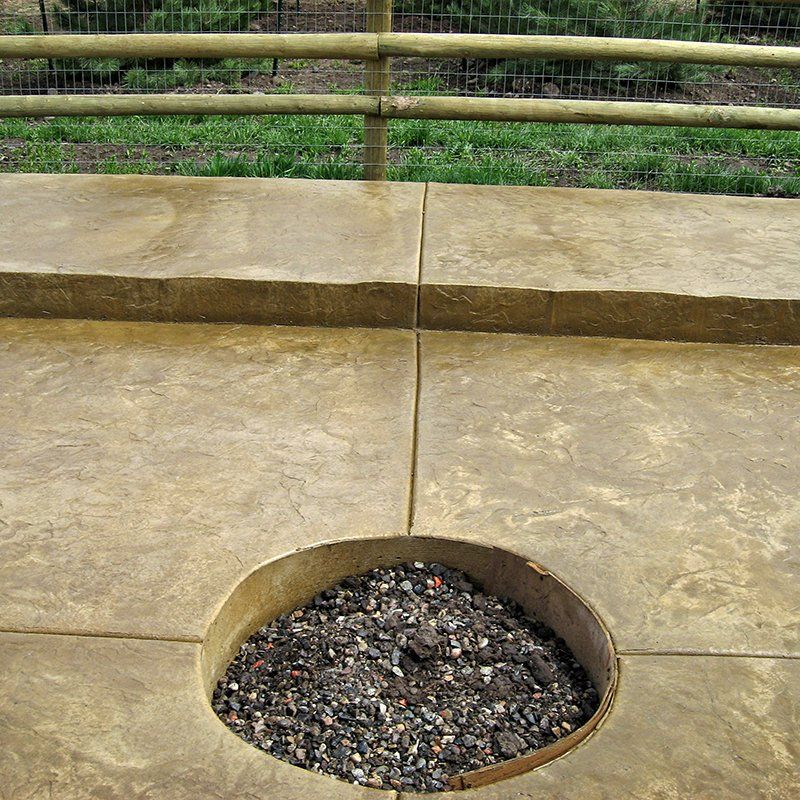 A concrete patio with a hole in the middle filled with rocks