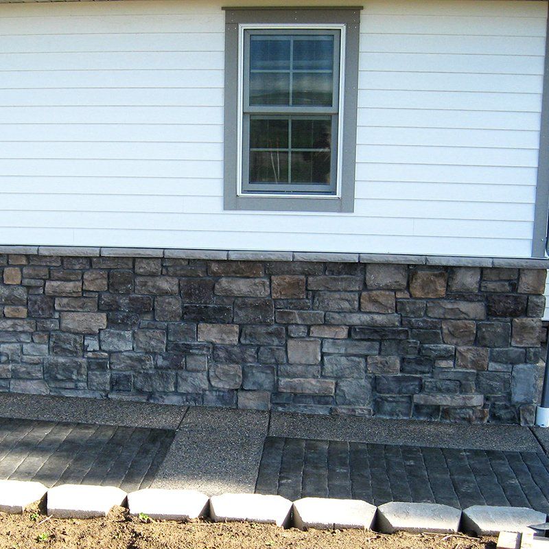 A white house with a stone wall and a window