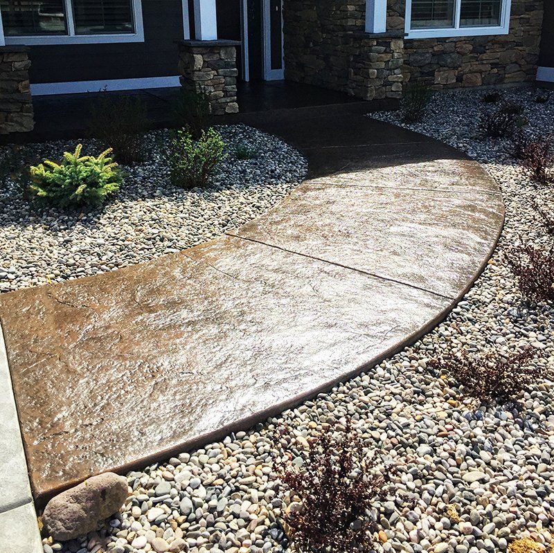 A concrete walkway surrounded by rocks in front of a house