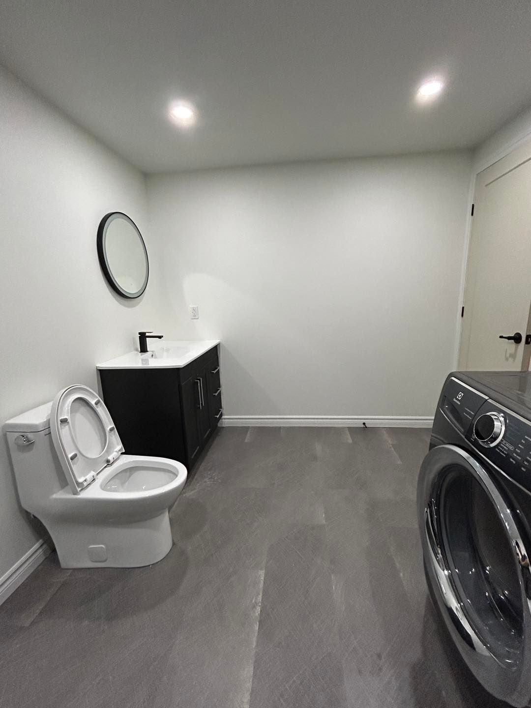 Une salle de bain avec WC, lavabo et laveuse et sécheuse.