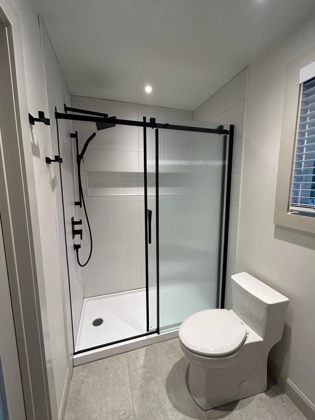 Une salle de bain avec WC, douche et fenêtre.