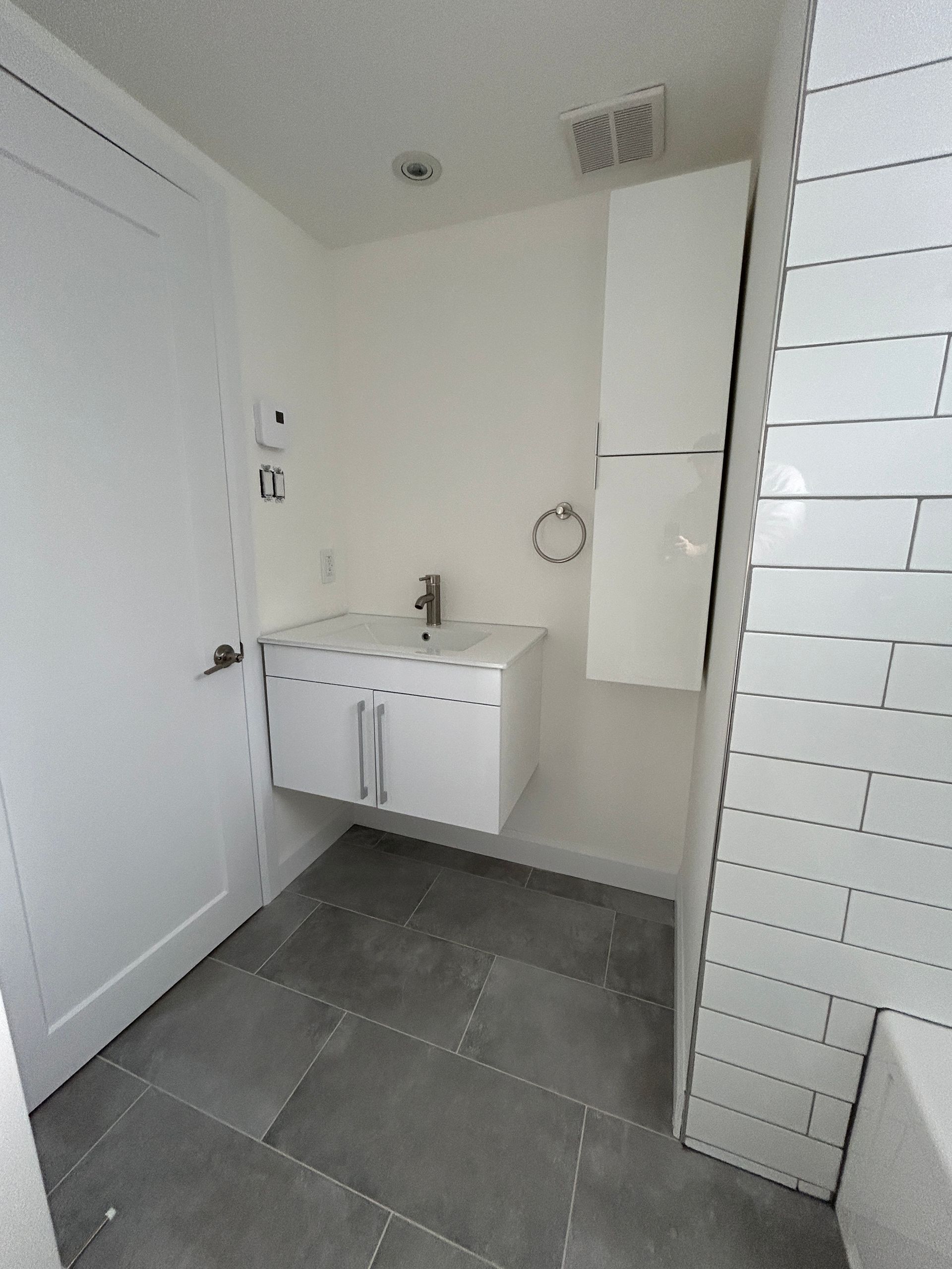 Une salle de bain avec un lavabo, des armoires et une porte