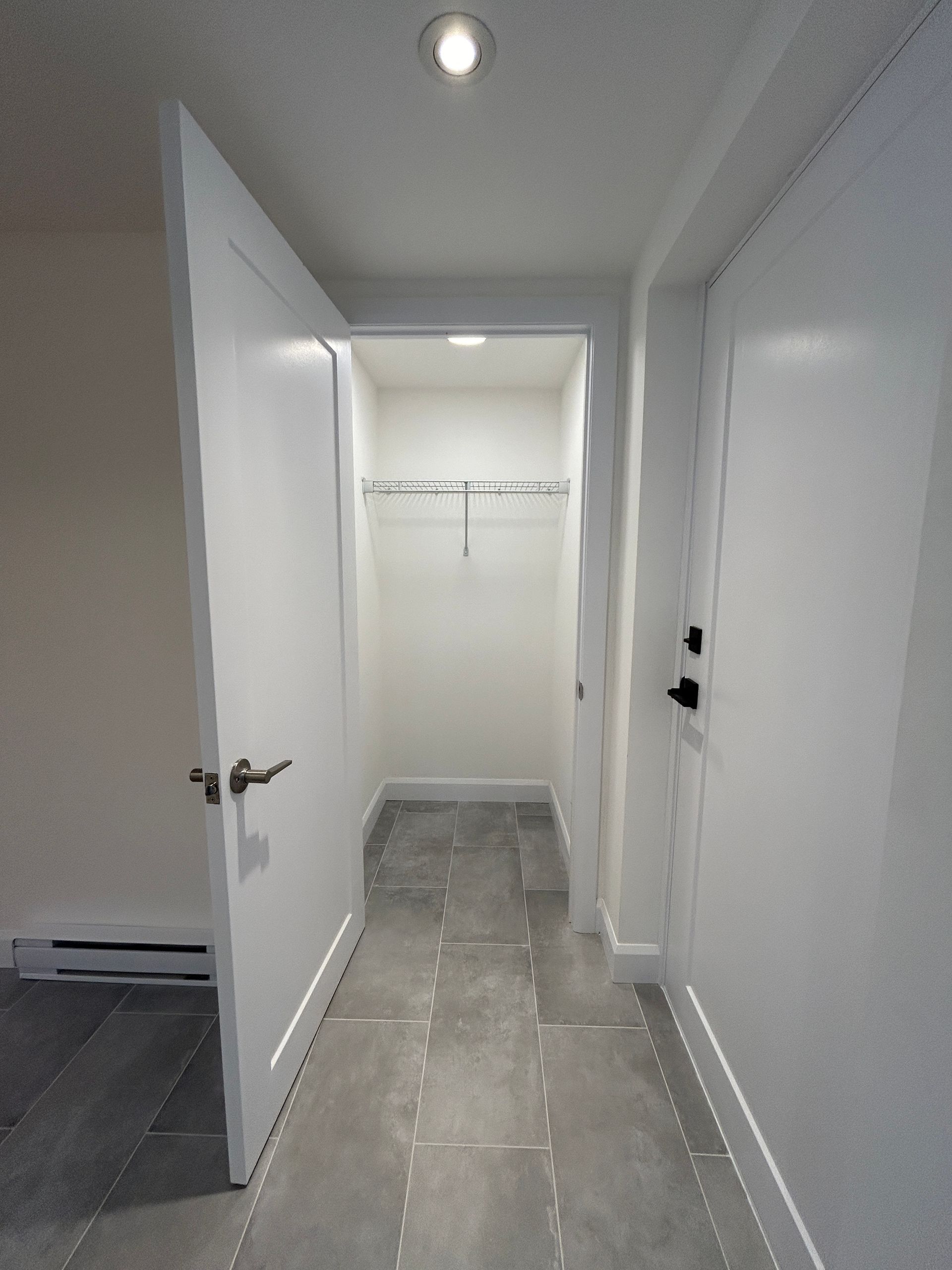 Un couloir avec des murs blancs et un sol en carrelage gris