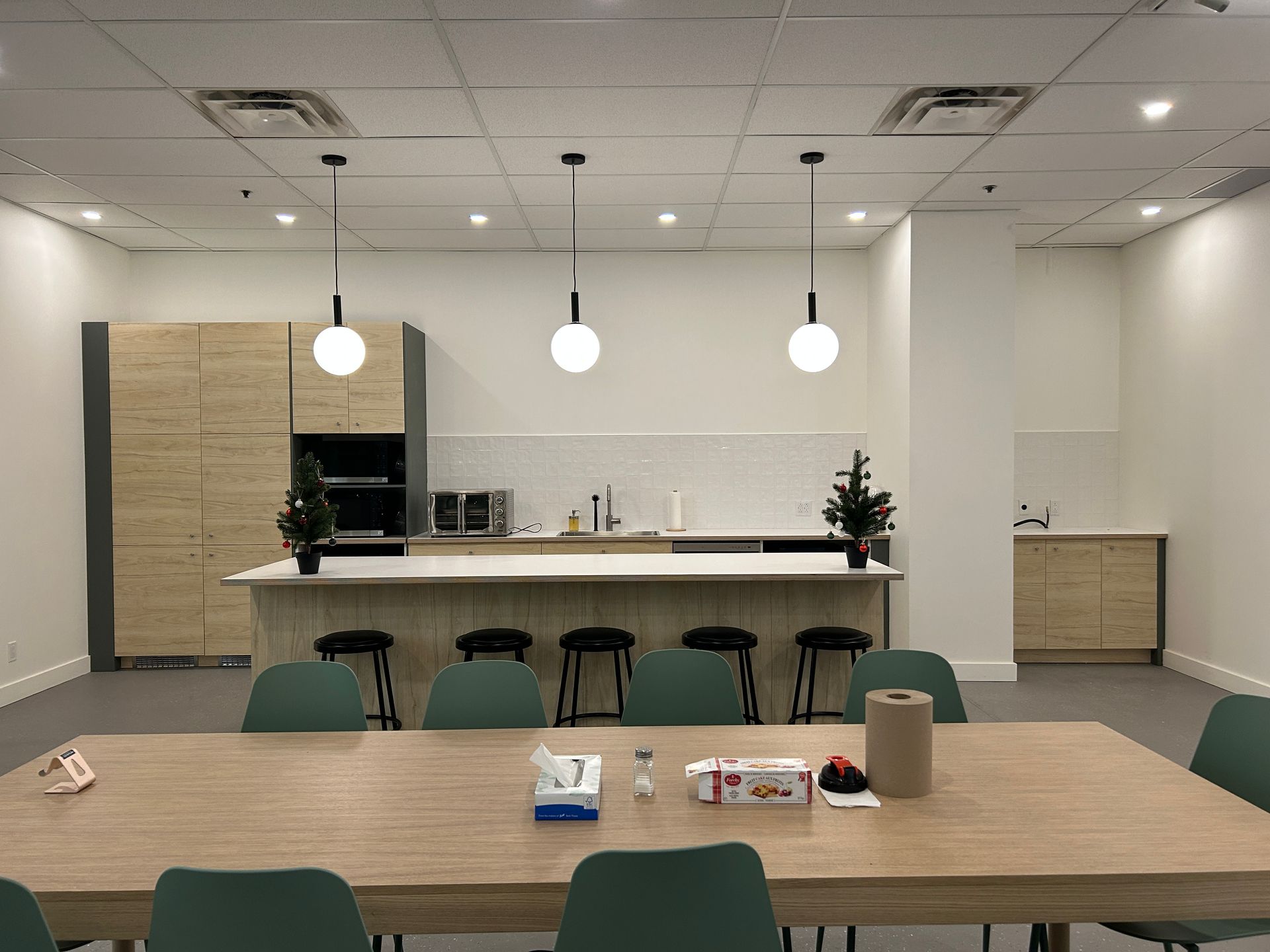 Une pièce avec une table et des chaises et une cuisine en arrière-plan.