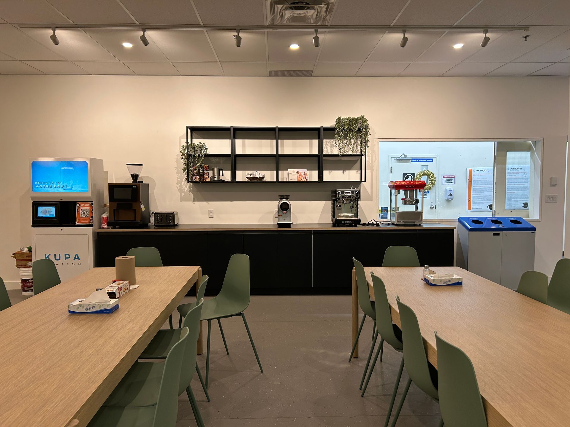 Une salle à manger avec tables et chaises et une cuisine en arrière-plan.