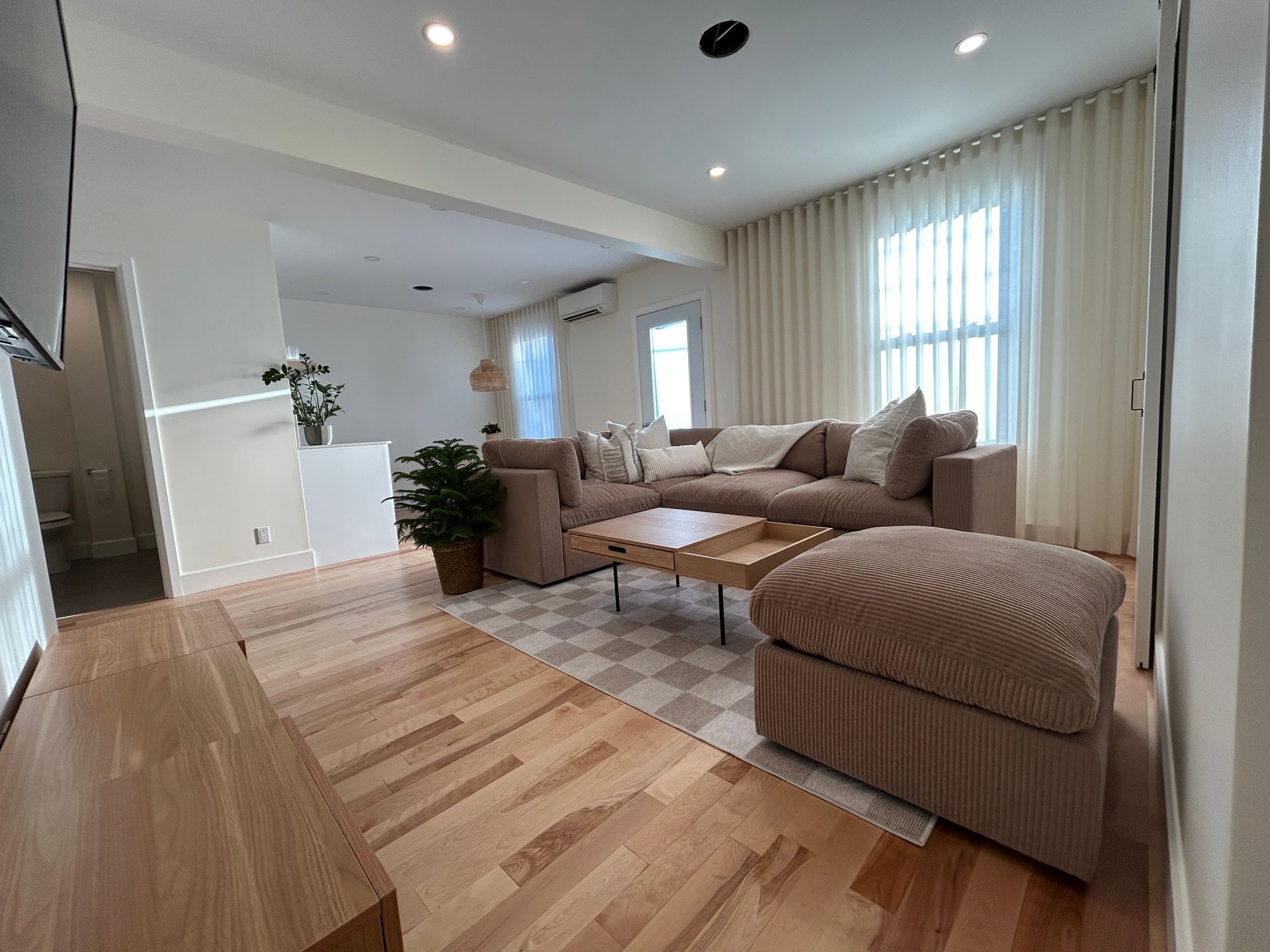 Un salon avec un canapé, un pouf, une table basse et une télévision.