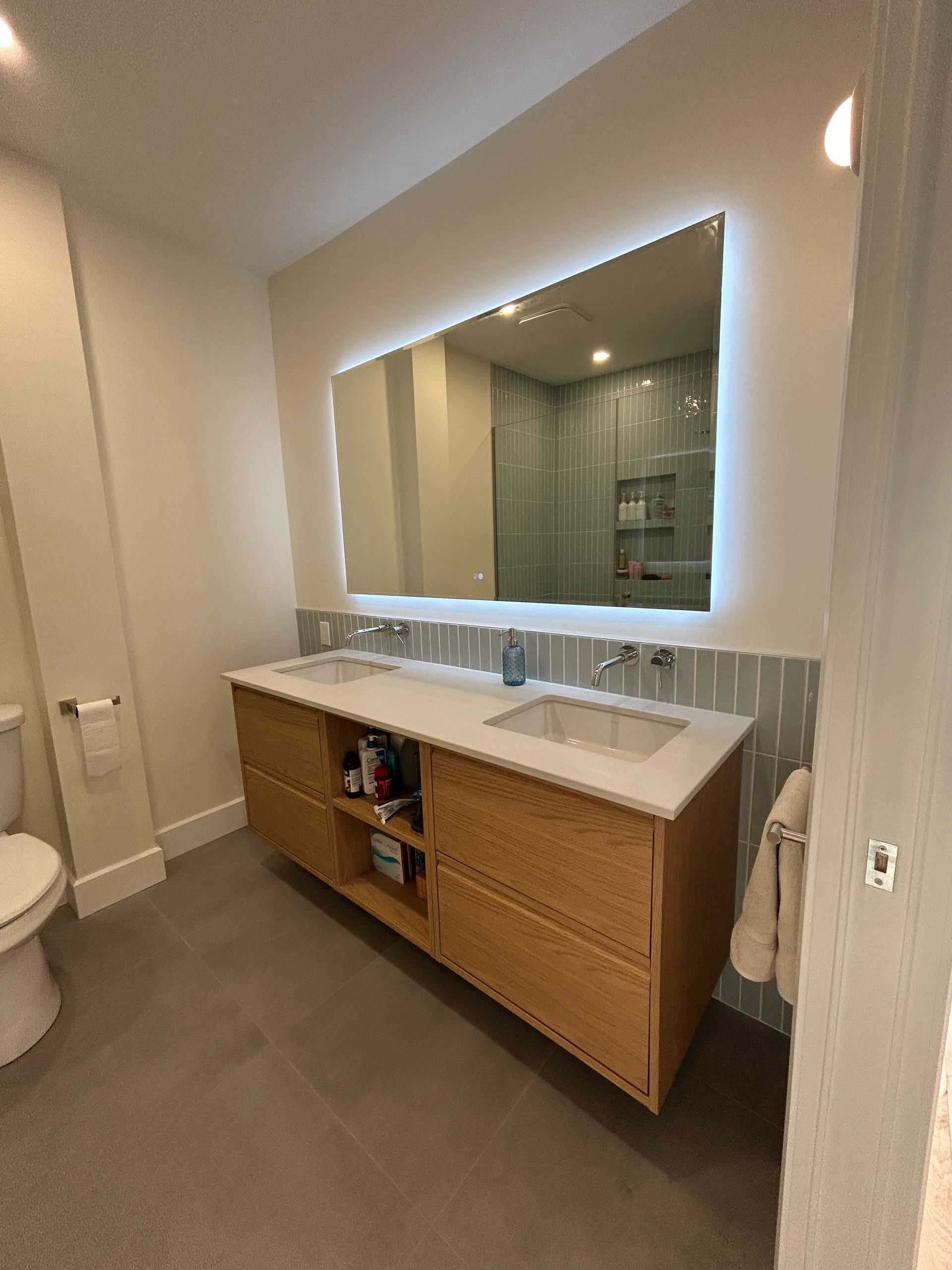 Une salle de bain avec deux lavabos, un WC et un grand miroir.