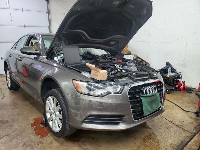 A gray audi with the hood open in a garage