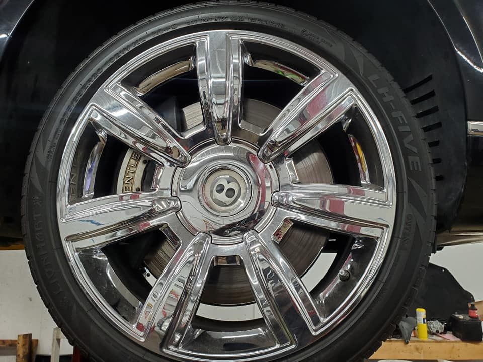 A bentley is sitting on a lift with a tire on it.