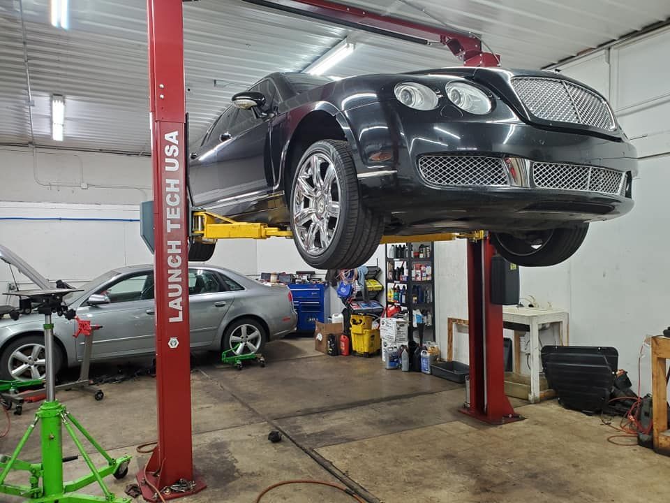 A bentley is sitting on a lift in a garage.