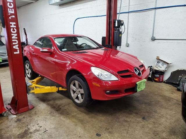 A red mercedes is sitting on a lift in a garage
