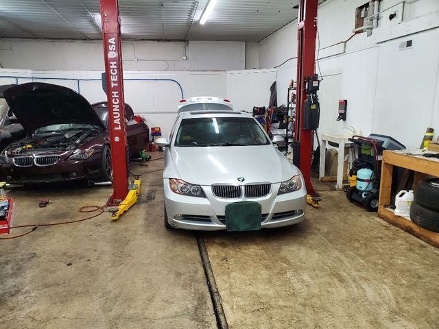 A silver car is sitting on a lift in a garage.