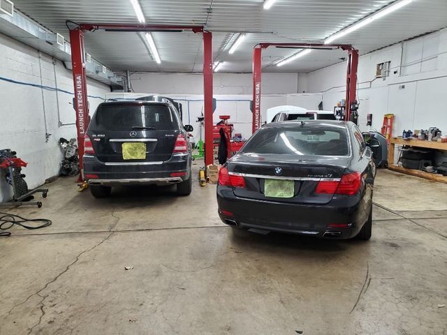Two cars are on a lift in a garage.