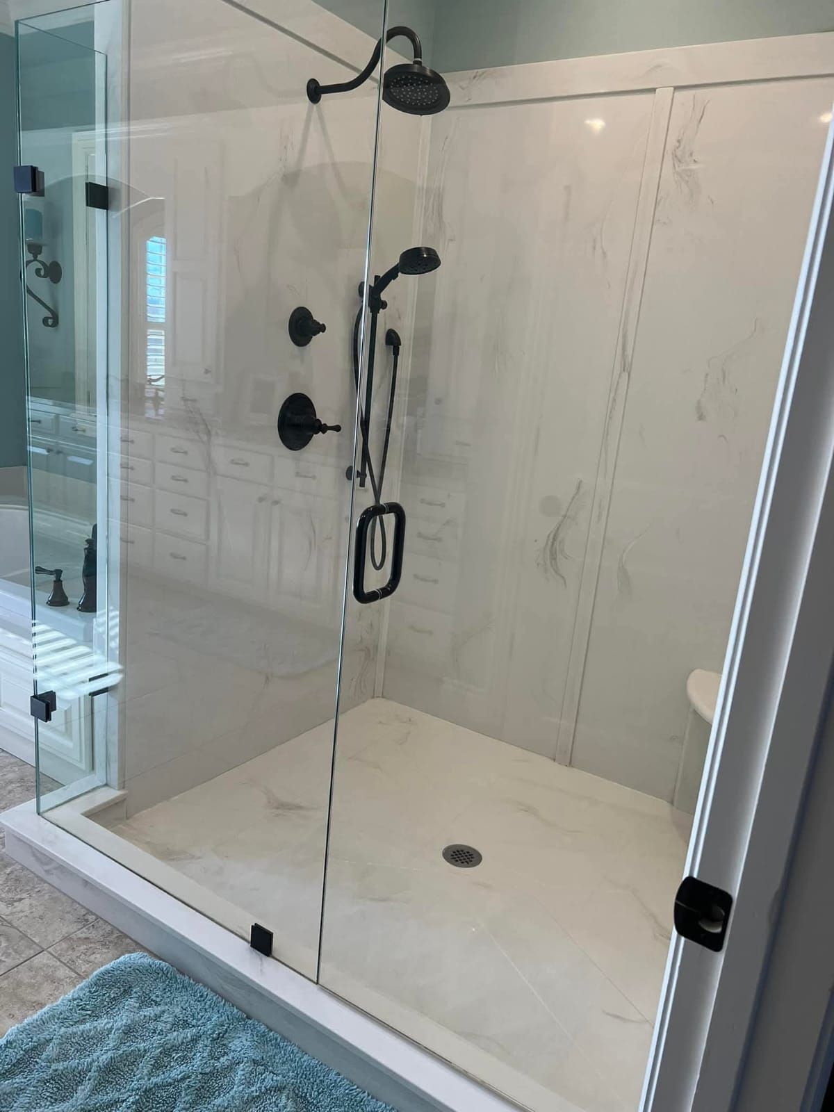 A bathroom with a walk in shower with a glass door.