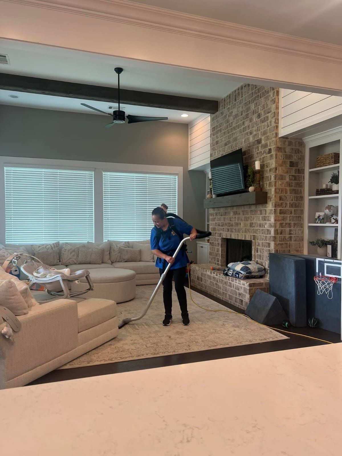 A man is cleaning a living room with a vacuum cleaner.