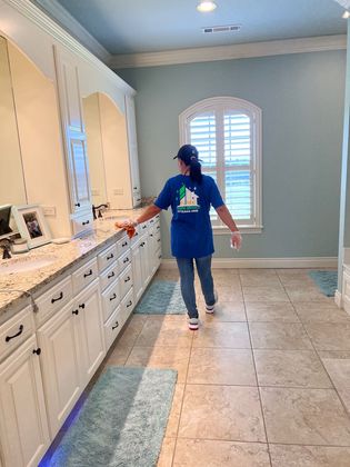 A woman in a blue shirt is standing in a bathroom.