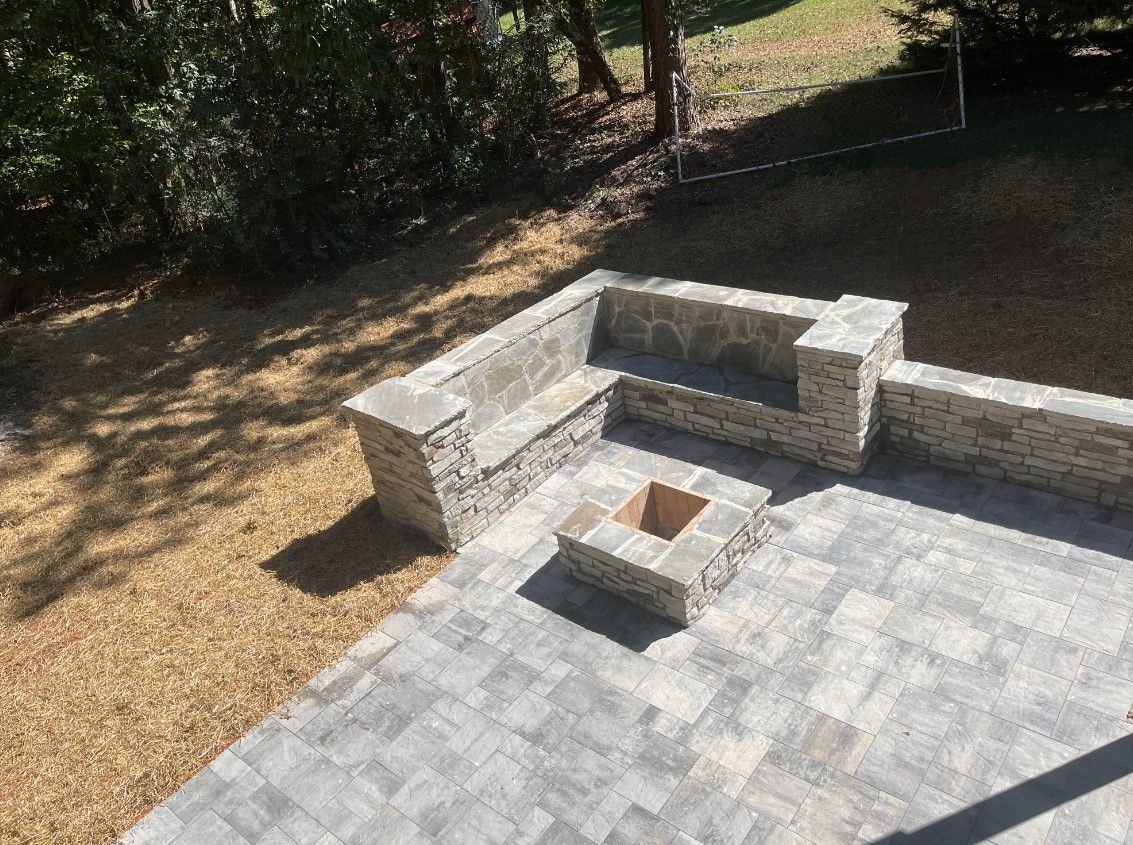 Stone patio with built-in bench around a square fire pit.