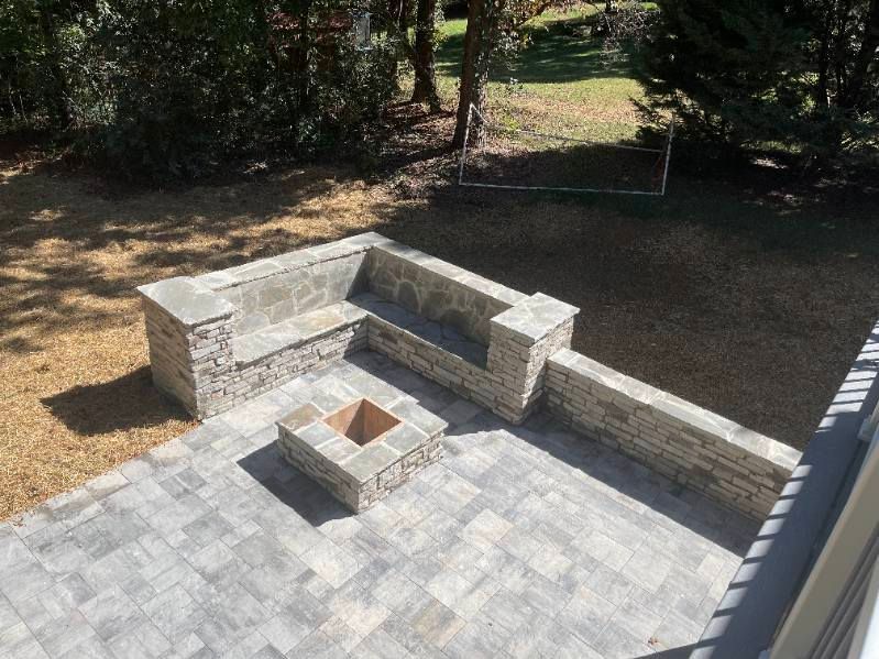Stone patio with built-in seating, a fire pit, and gravel area.