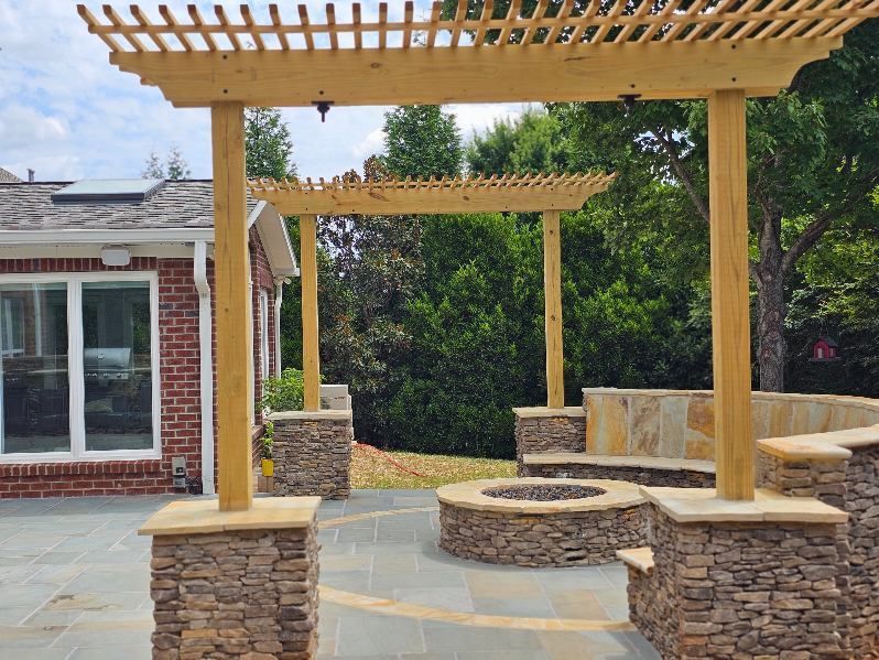 Outdoor patio with stone columns, a wooden pergola, and a fire pit.