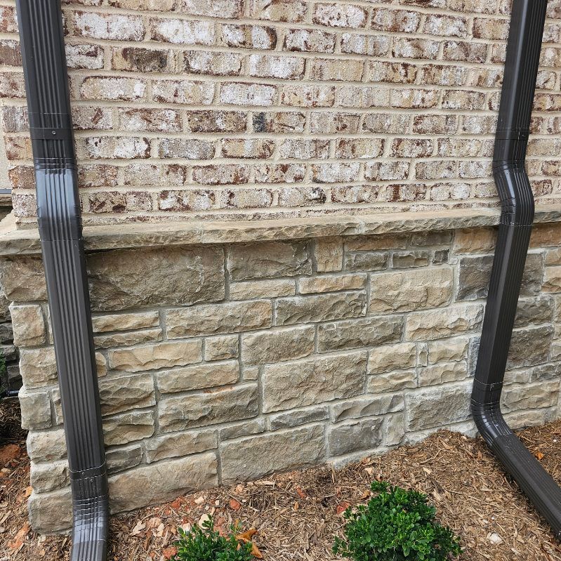 Brick and stone exterior wall with dark gutters.