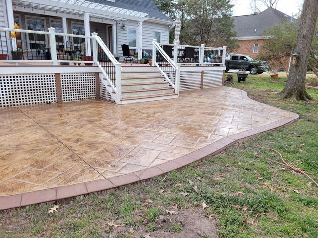 Stamped concrete patio with a border, beside a house with a deck.