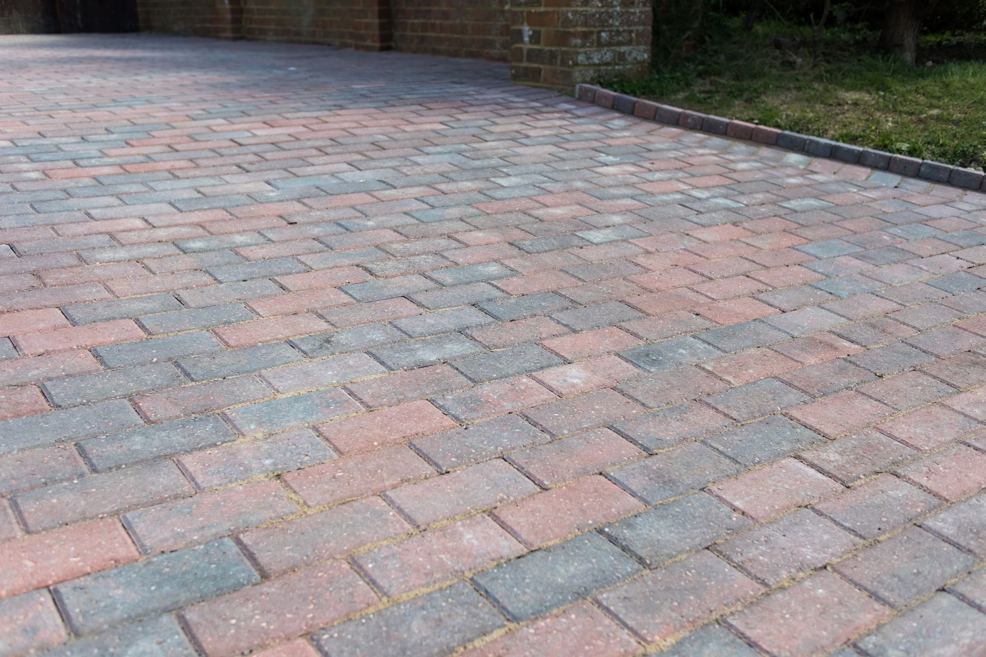 Brick paved driveway with mixed red and gray rectangular bricks.