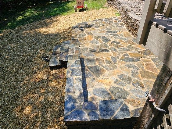 Stone steps leading to a structure, set in a grassy yard.