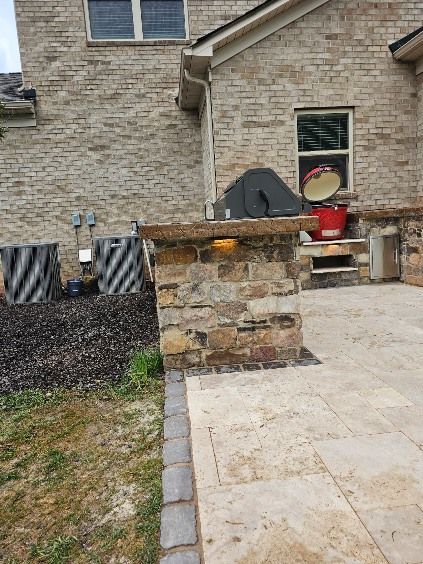 Outdoor brick pillar on a patio, with a house in the background. Air conditioning units and grill visible.