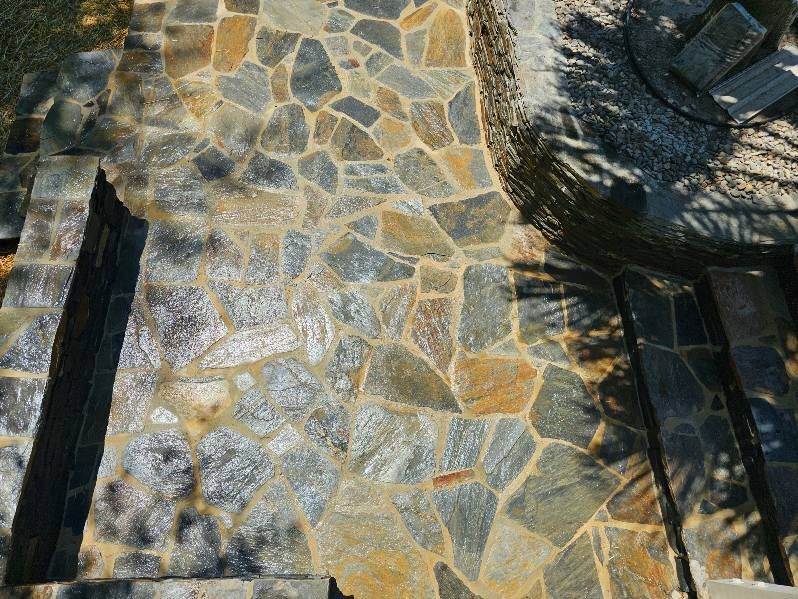 Stone path with irregular shapes, transitioning to steps, shaded by foliage.