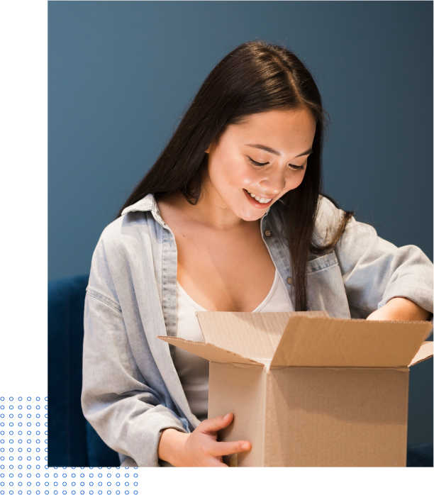 A woman is opening a cardboard box and smiling.