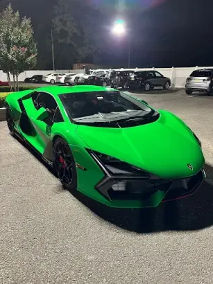 Bright green Lamborghini parked in a lot at night.