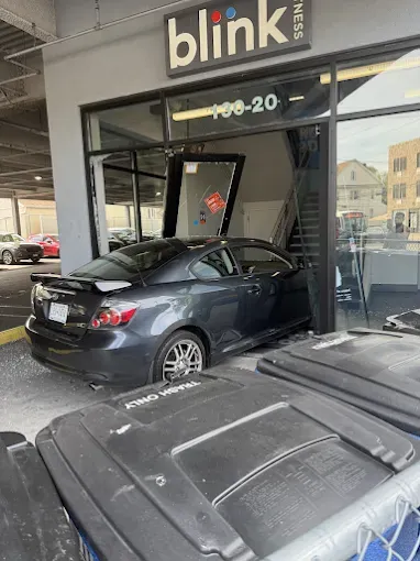 Woman in straw hat smiles, holding wine glass near a lake.