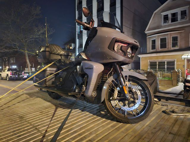Gray motorcycle parked on a brick-paved street at night. Police tape in the background.