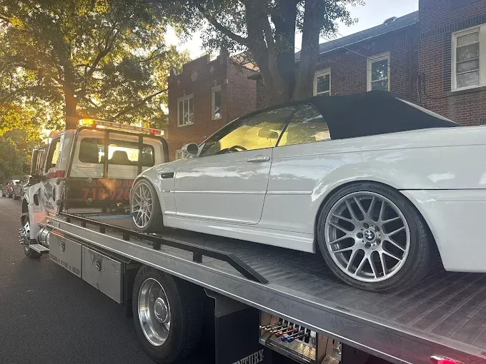 Woman in straw hat smiles, holding wine glass near a lake.