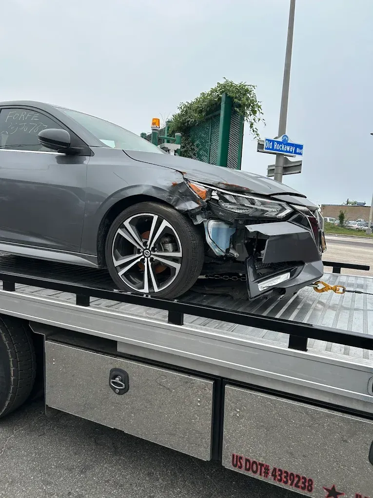 Woman in straw hat smiles, holding wine glass near a lake.