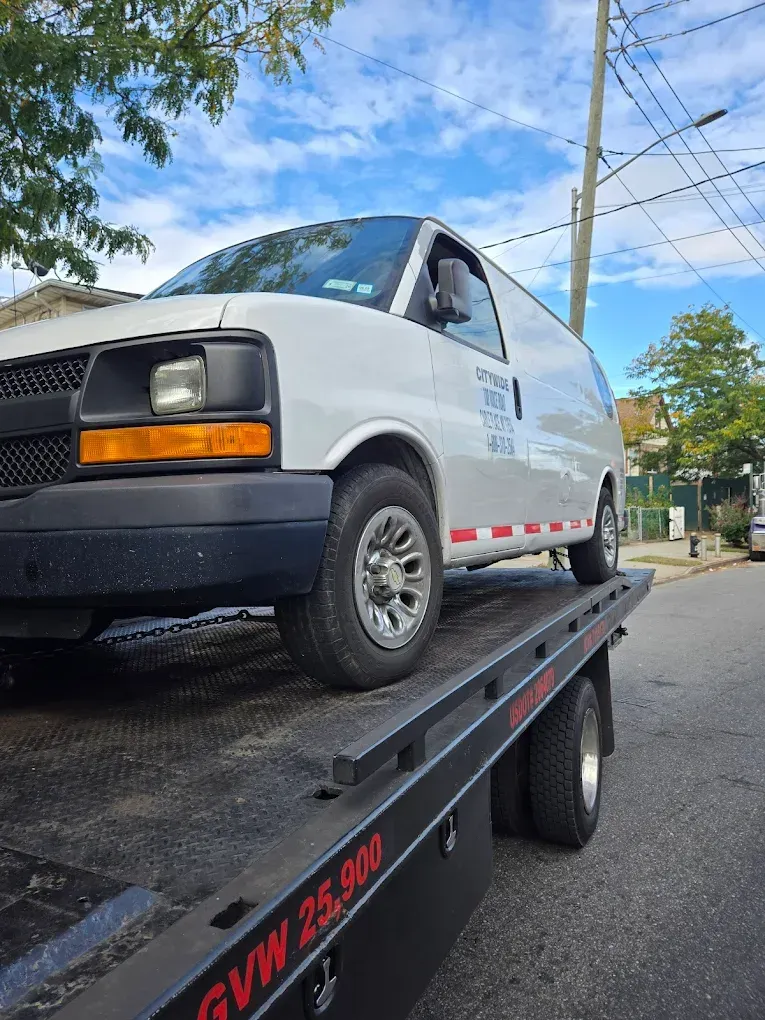 Woman in straw hat smiles, holding wine glass near a lake.