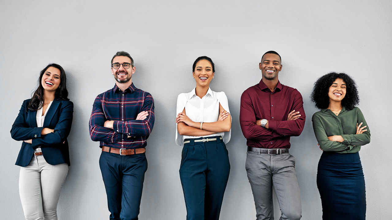 Five diverse professionals, arms crossed, lean against a gray wall, smiling confidently.