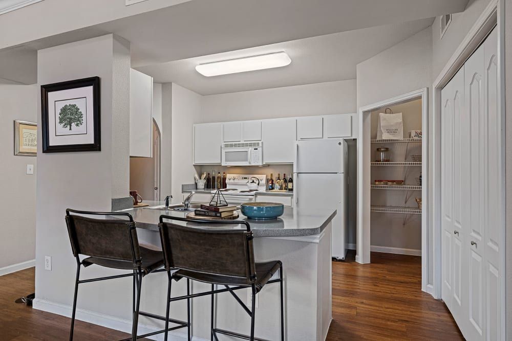 a kitchen with a bar and stools and a refrigerator at Marquis Parkside in Austin, TX.