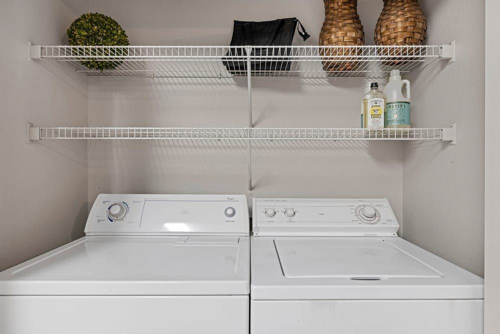a laundry room with a washer and dryer and shelves at Marquis Parkside in Austin, TX.