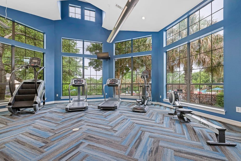 a gym with treadmills, exercise bikes, and a staircase at Marquis Parkside in Austin, TX.
