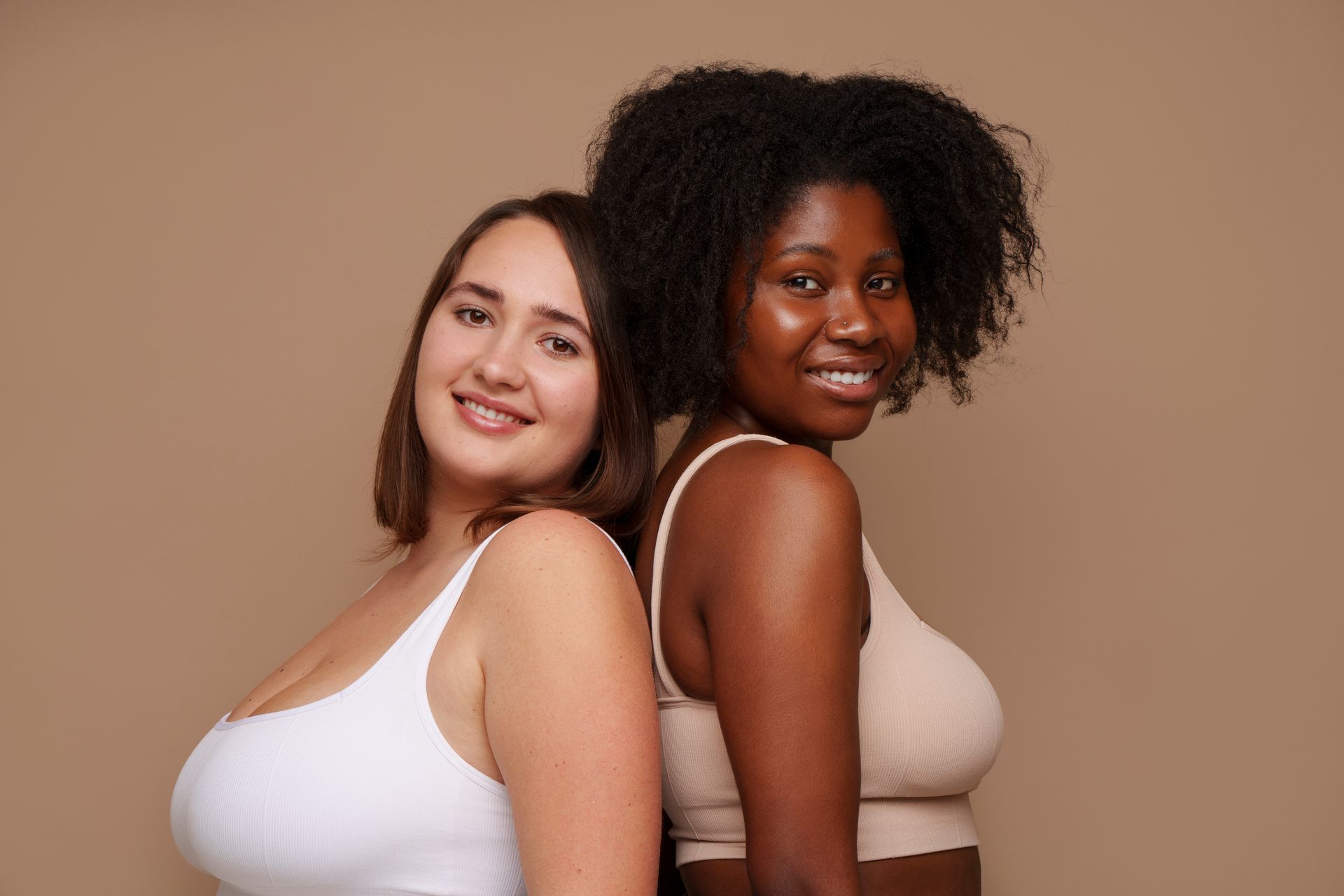 Two women are standing back to back and smiling for the camera.